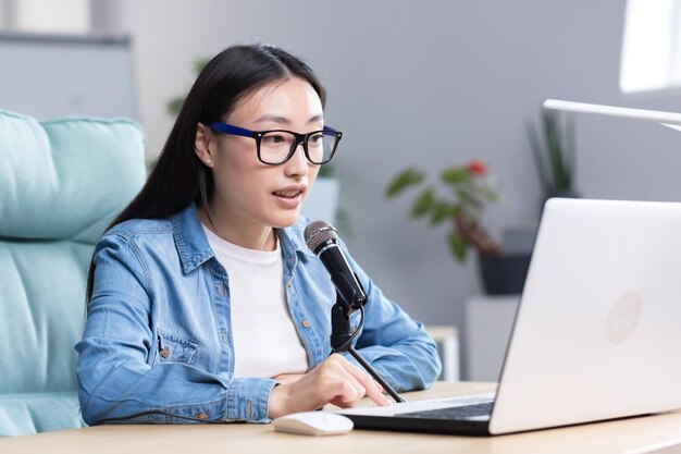 Podcast recording interview young beautiful asian woman sitting at a table with a microphone and a