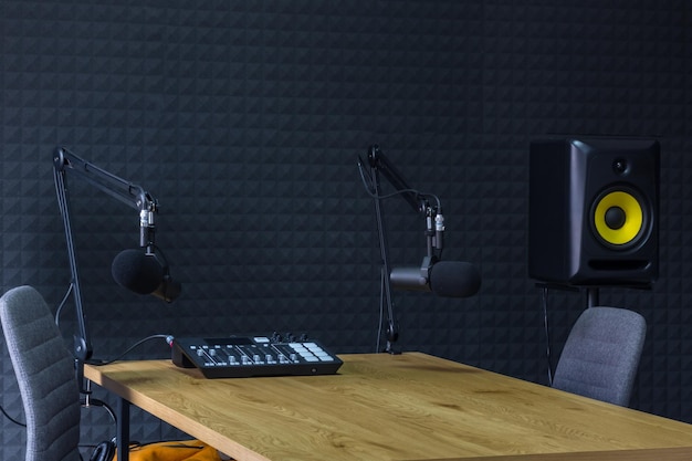 Podcast recording studio with microphones and equalizer for\
recording online radio broadcasts with black soundproof wall