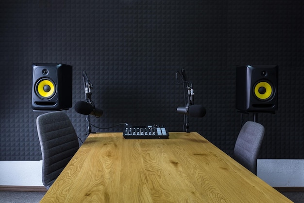 Photo podcast recording studio with microphones and equalizer for recording online radio broadcasts with black soundproof wall