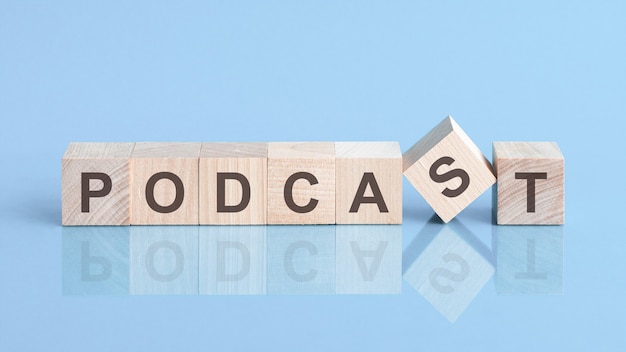 Podcast word is made of wooden building blocks lying on the blue table, concept