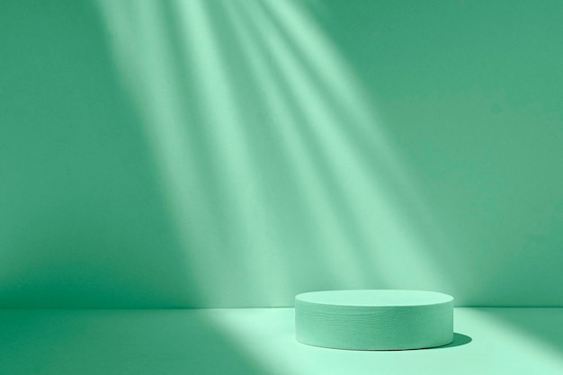 Podium cylinder in a beam of light on a green background with shadows and light to show the product