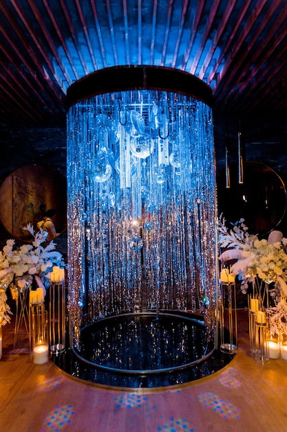 Podium made of shiny rain tinsel event decoration with candle decor and floristry illuminated with blue lightxA