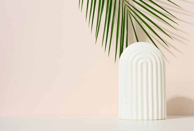 Podium met witte bogen om cosmetica, producten en andere koopwaar te presenteren. Groen palmblad