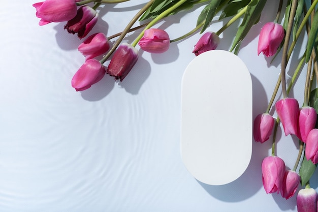 Podium of voetstuk met waterrimpel en tulpen plat bovenaanzicht Cosmetische sjabloon kopieerruimte