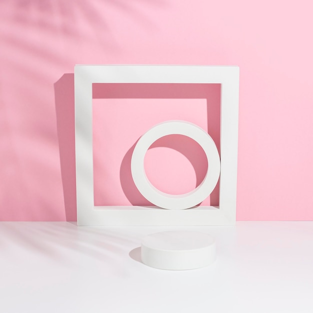 Podium white square circles for presentation under the shadow of palm leaves on a white pink background