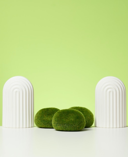 Podium with moss and arches to showcase cosmetics, products and other goods. Green background