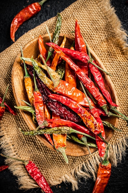 Pods of dried chili peppers in a wooden plate on a napkin