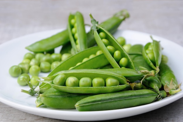 Pods of fresh green peas on a plate