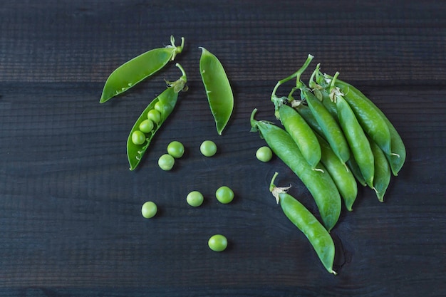 Photo pods of green peas and pea on a dark wooden surface