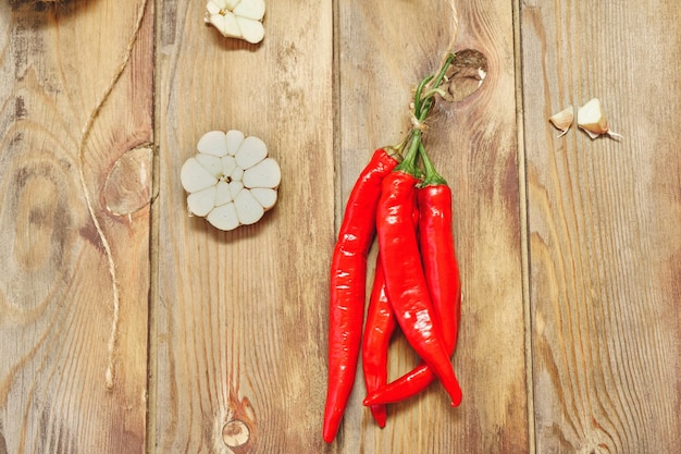 Pods of red chili pepper and garlic cut in half on a wooden background