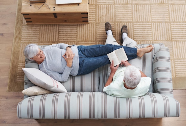 Poetry is the language of love A senior man reading to his wife as she she lies on the couch