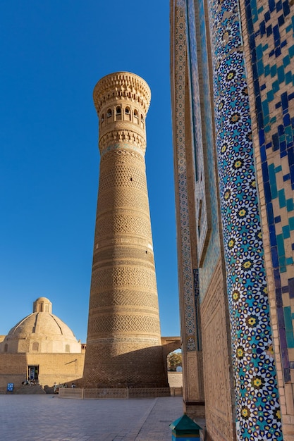 Piazza poikalyan di giorno con il minareto kalyan, capolavoro del patrimonio illuminato dal sole, bukhara, uzbekistan