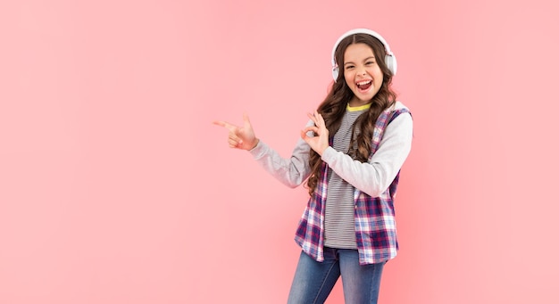 Point finger on copy space new technology childhood development child in modern earphones online education back to school happy teen girl in headphones music lover listen to music