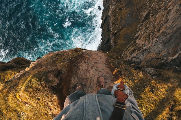 Point of view from the top of a standing man at the edge on a cliff