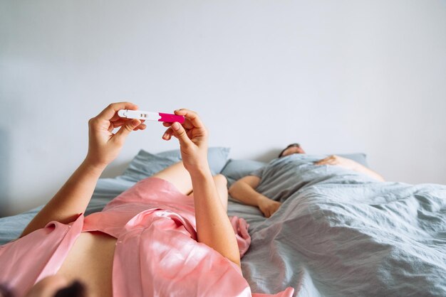 Point of view woman looking on positive pregnancy test man slipping on background