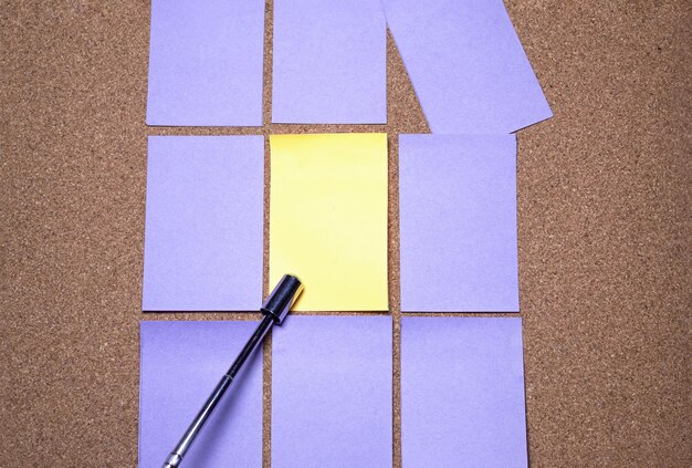 Foto un puntatore indica un postit giallo vuoto circondato da una griglia imperfetta di postit viola