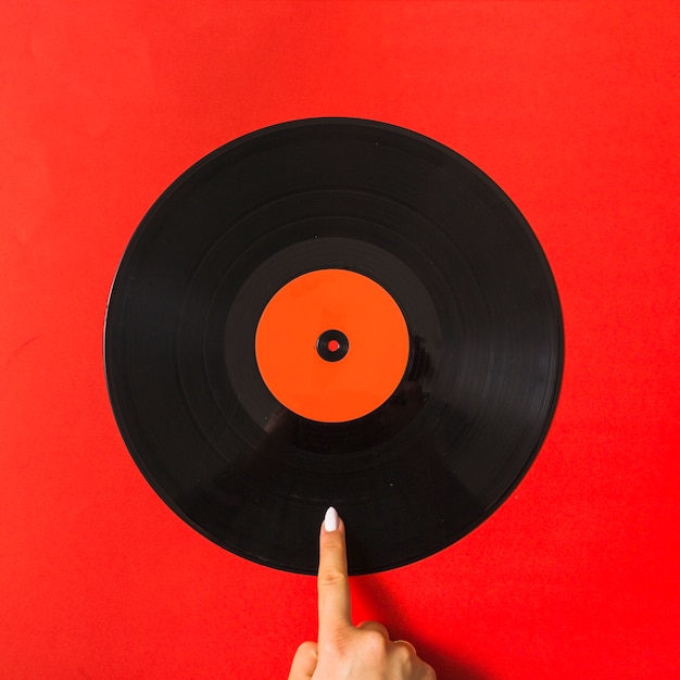 Photo pointing finger on vinyl record over red background