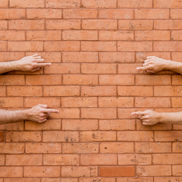 Pointing fingers at each other on brick wall