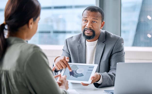 Pointing out problems based on market research Shot of a mature businessman speaking to a colleague while analysing graphs on a digital tablet in an office