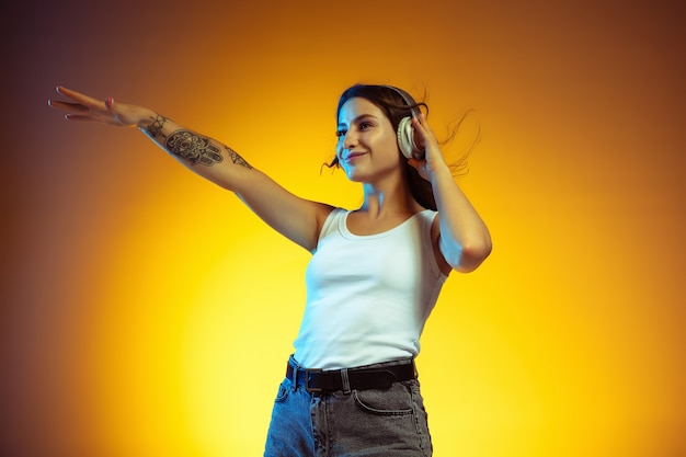 Pointing. Portrait of young caucasian woman isolated on gradient yellow studio wall.