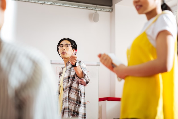 Pointing at speaker. Calm experienced teacher conducting a seminar and pointing to the speaker while looking at her