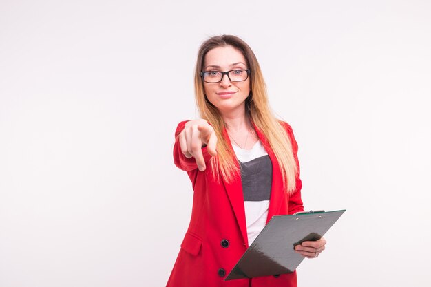 Pointing stylish business lady with documents in red fashionable suit and glasses on white background.