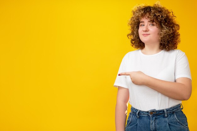 Pointing woman commercial background advertisement choice body positive cheerful smiling overweight girl with curly hair presenting product on orange copy space