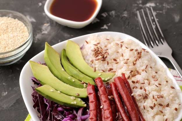 Poke bowl Hawaiian food a plate of rice salmon avocado cabbage and cheese near skunk and soy sauce