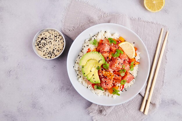 Foto poke bowl met zalm of tonijn, rijst, avocado, sesamzaad, micro-groenen, hawaiiaans dieet, eten met vis, pokebowl.