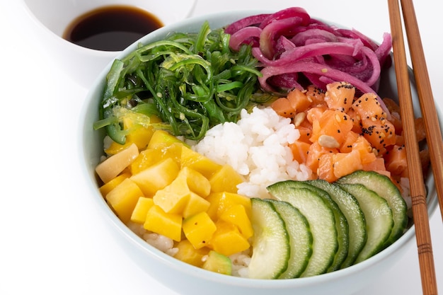 Poke bowl con riso salmonecetriolomangoonionwakame insalata semi di papavero e semi di girasoli isolati su sfondo bianco