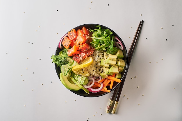 Poke bowl with salmon, avocado, isolated over white background. top view