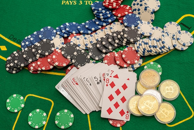 Poker cards scattered with money colored chips on a green poker\
table