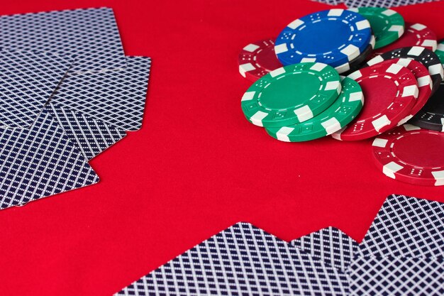 Foto fiches da poker e carte da gioco su un tavolo rosso