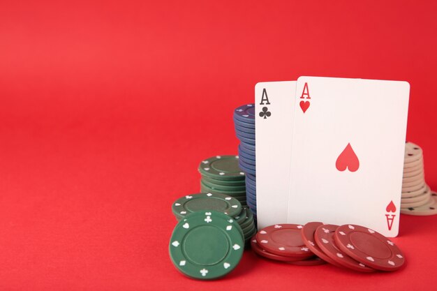 Poker chips and playing cards on red wall. Casino