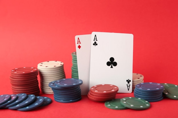 Poker chips and playing cards on red wall. casino