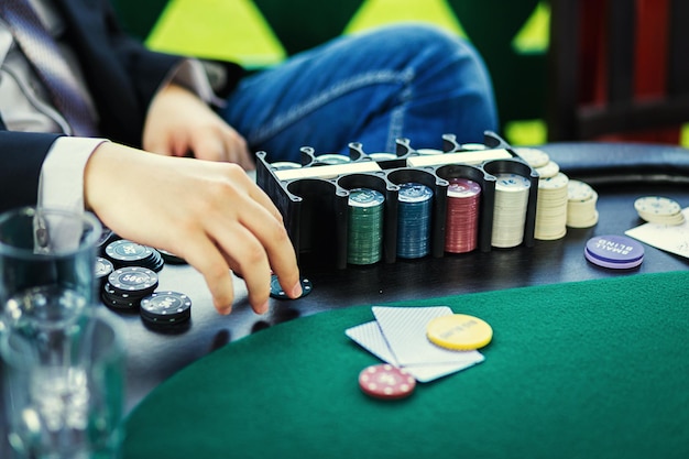 Poker chips on table with hands and cards in casino