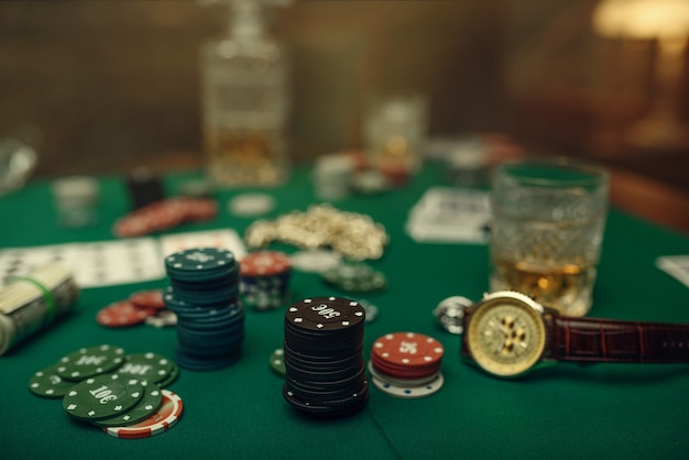 Poker concept, money bet, cards and chips on gaming table, whiskey and cigar in casino.