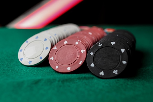 Concetto di gioco di poker. concetto di casinò. pila di fiches da poker a luce rossa sul tavolo da poker del gioco.