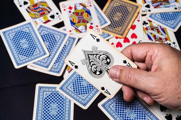 Poker kaartspel op een tafel, hand met een schoppen aas met kaarten op tafel liggen