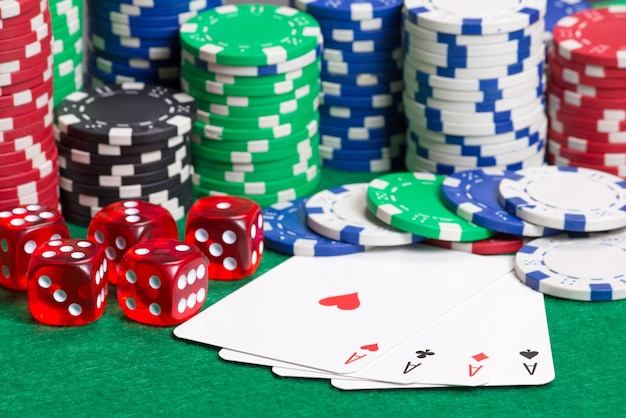 Poker kleurrijke chips dobbelstenen en vier azen op de groene tafel