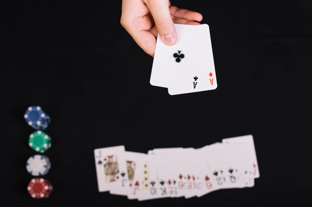 La mano del giocatore di poker che tiene le carte da gioco sul fondale nero