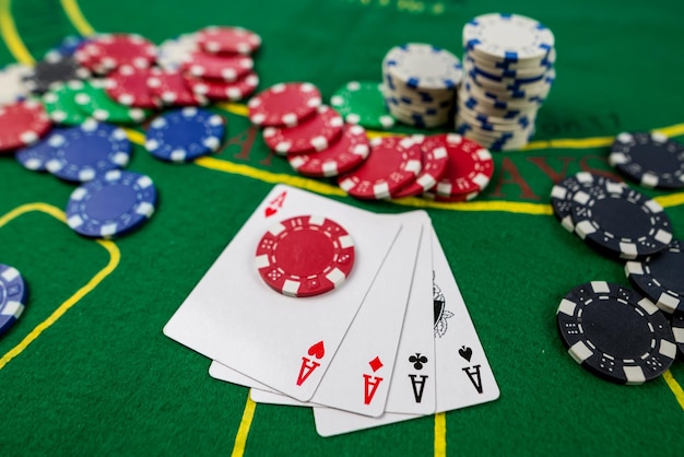 Poker speelkaarten en chips op groene tafel Texas holdemVier azen op een groene tafel in een casino met chips gokken