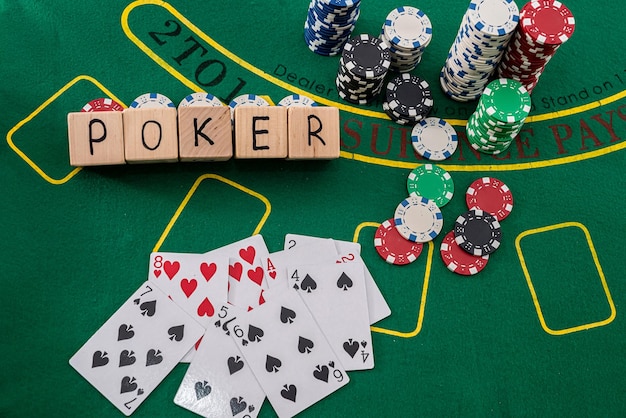 Poker text on wooden cubes with poker chips and playing cards on green casino table. gambling