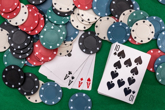 Pokerfiches en vier aas op groene tafel