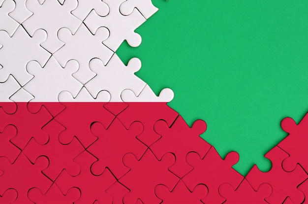 Poland flag  is depicted on a completed jigsaw puzzle with free green copy space on the right side