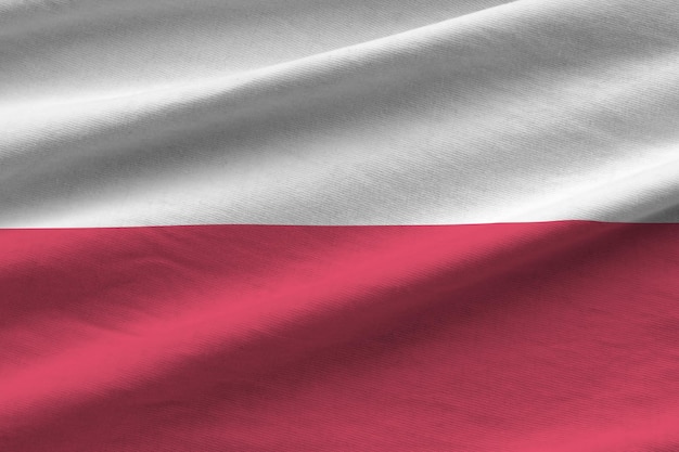 Poland flag with big folds waving close up under the studio light indoors The official symbols and colors in banner