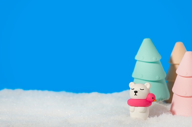 Polar toy bear with Christmas trees in the snow on blue.