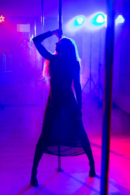 Pole dance Young slender sexy woman dancing on a pole in the interior of a nightclub with light