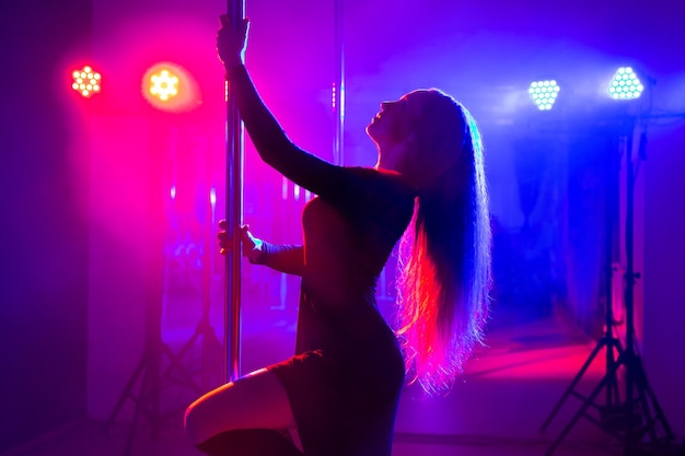 Pole dance Молодая стройная сексуальная женщина танцует на шесте в интерьере ночного клуба