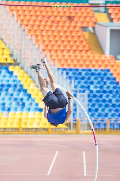 Photo pole vault a bearded athletic man rest against the ground on the pole